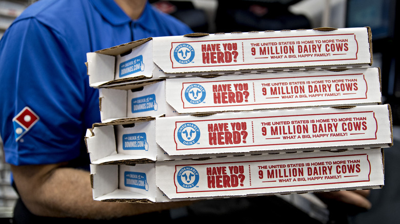 Delivery person holding four Dominos pizzas