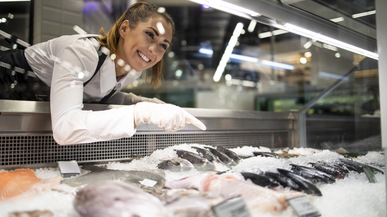 woman selling fish at the supermarket fish counter