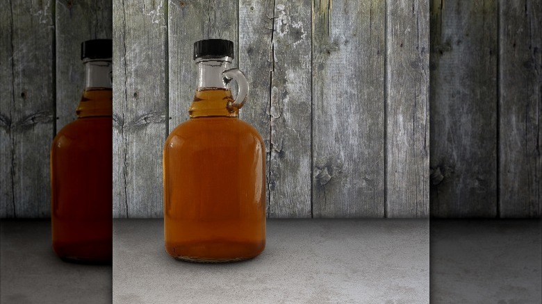 maple syrup jug in front of wood background