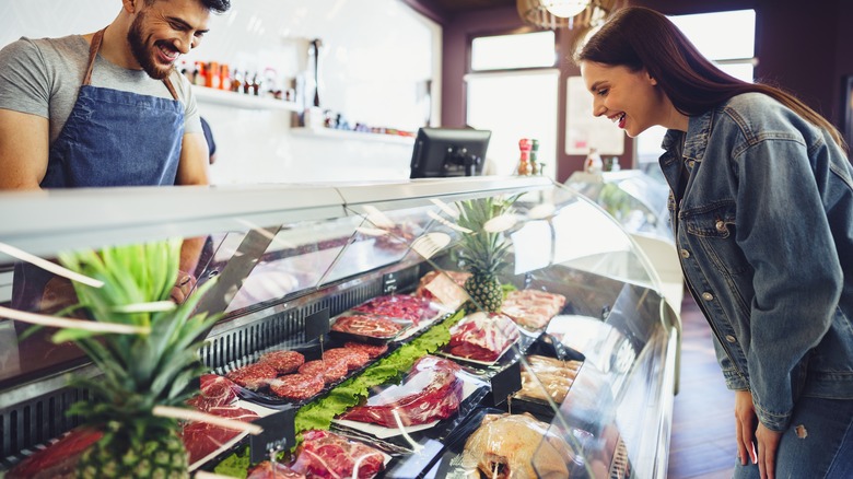 butcher serving woman from meat case