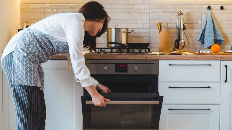 Woman opening an oven door 