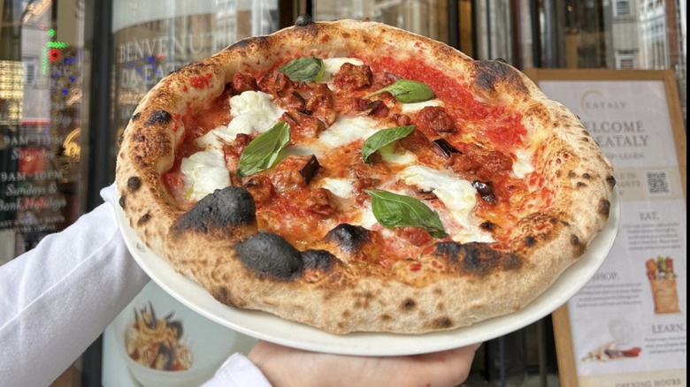 Person holding Eataly pizza pie