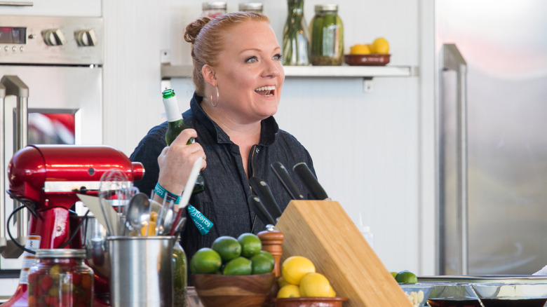 Tiffani Faison smiling at kitchen counter while holding bottle