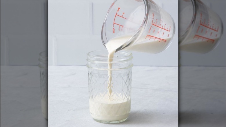 Hand pouring milk into jar