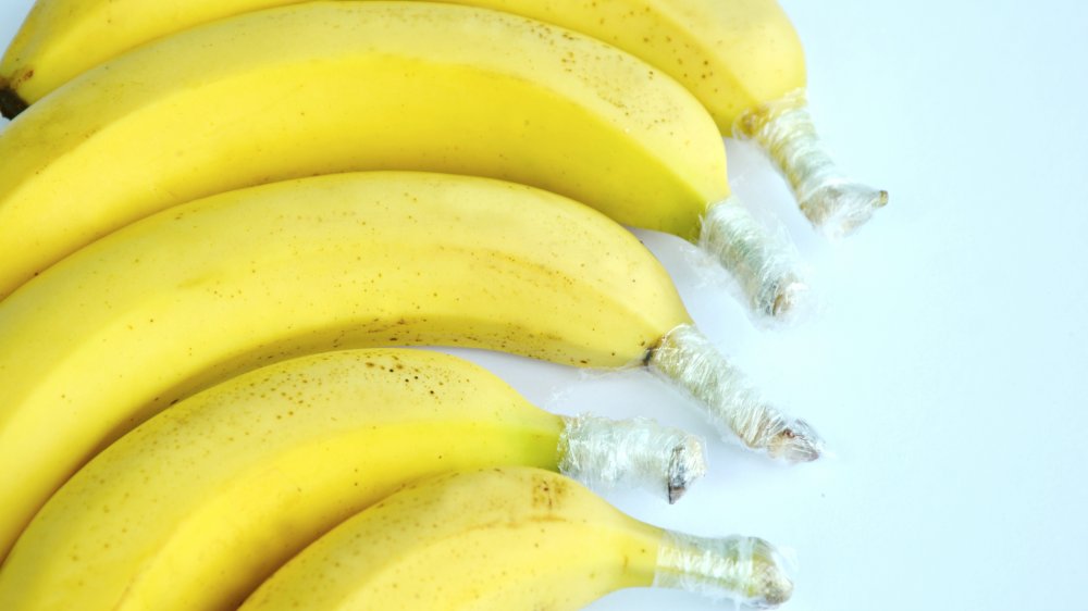 individual bananas with plastic-wrapped stems