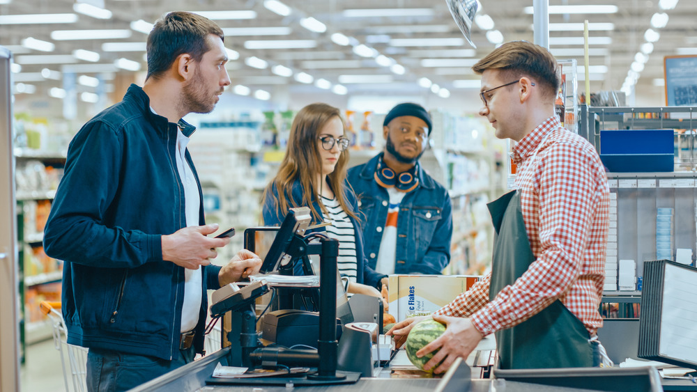 Grocery store cashier with line of customers