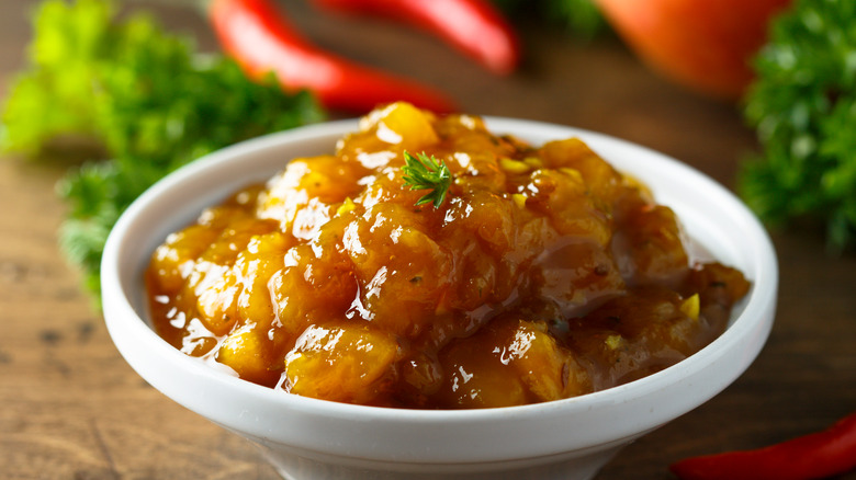 Small white bowl of chunky mango chutney.