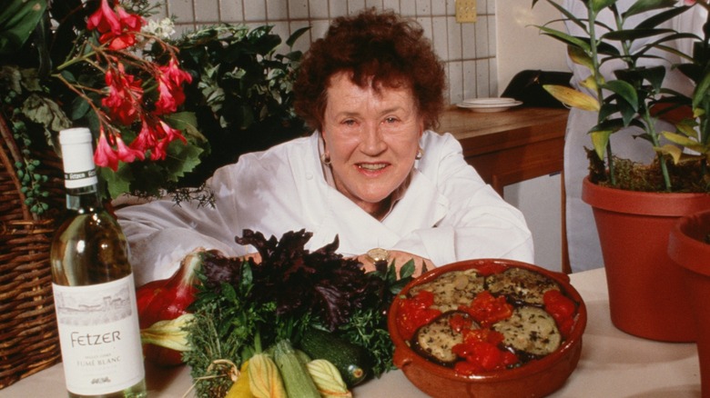 Julia Child smiling among French wine and food