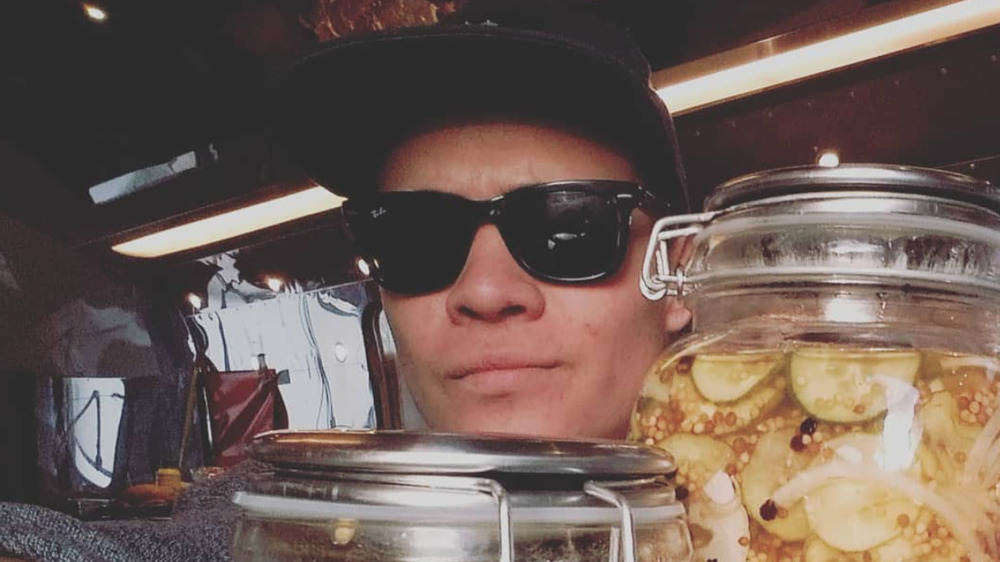 Cody Candelarion wearing sunglasses next to a jar of pickles