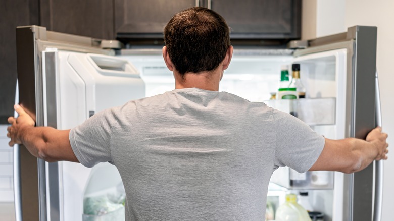 man looking inside his refrigerator