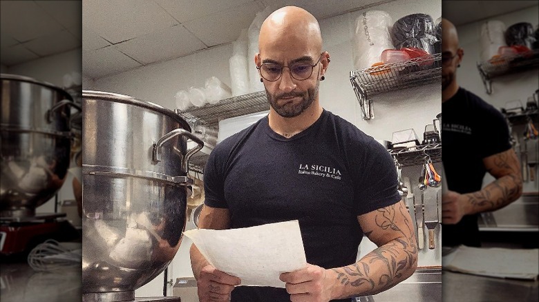 Diego Chiarello in a fitted black T-shirt looking at a paper intently