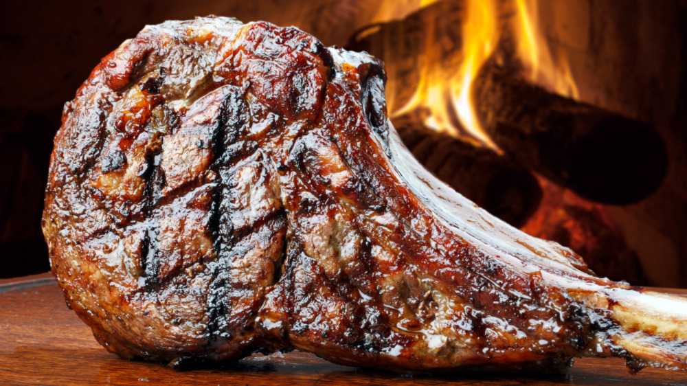 fresh grilled steak on a board in front of a fire