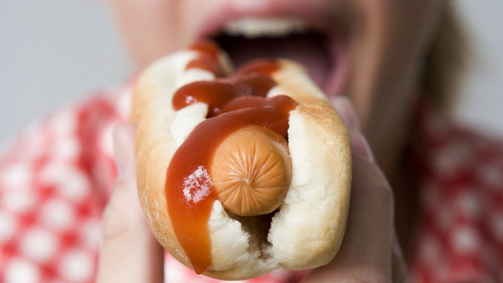 A woman eating a hot dog, like the ones at Five Guys