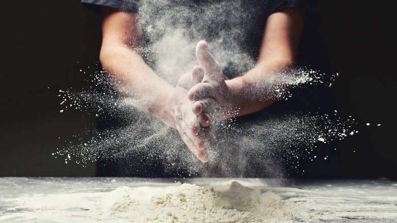 Person preparing flour for dough 