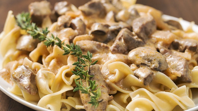 Beef stroganoff and noodles garnished with thyme