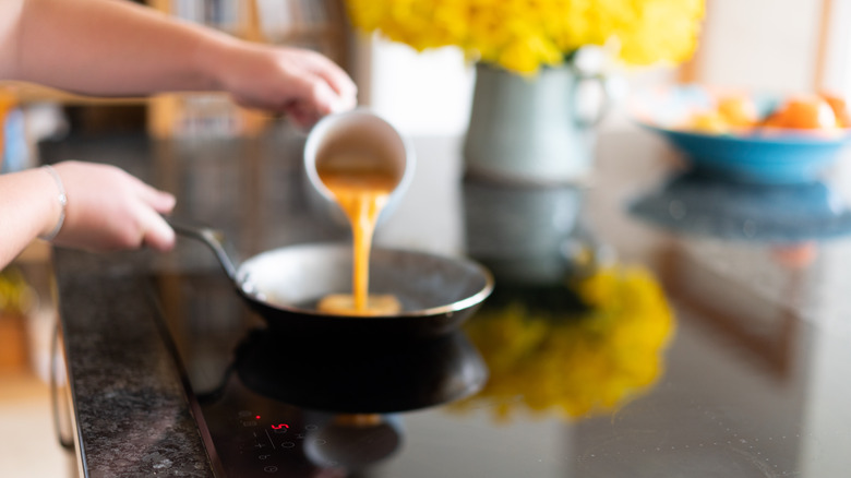 pouring eggs into frying pan