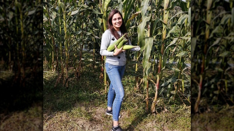 mariana alvarado carries corn in field