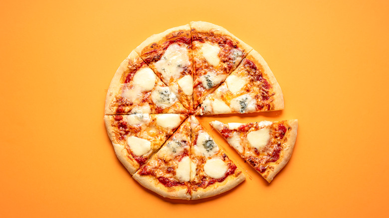 Pizza sliced up on yellow background 