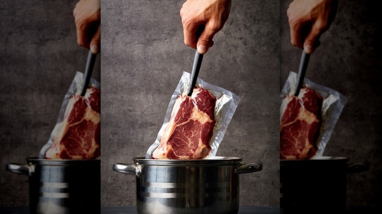 person lowering steak into pot