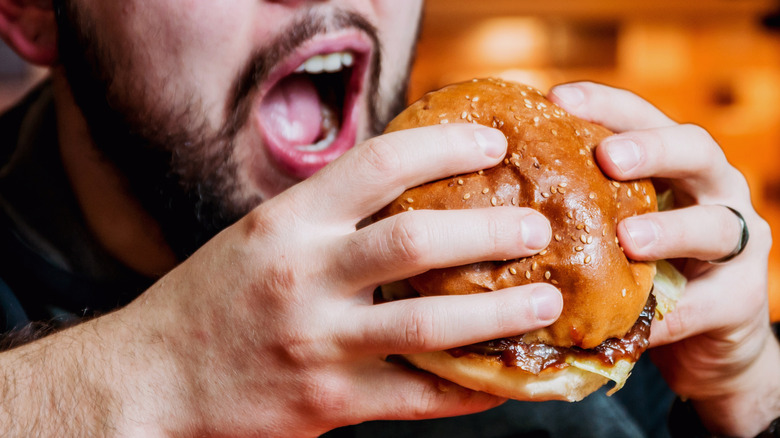 Man about to bite into a cheeseburger