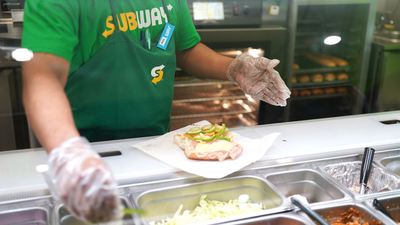 Subway worker behind the counter preparing a sandwich