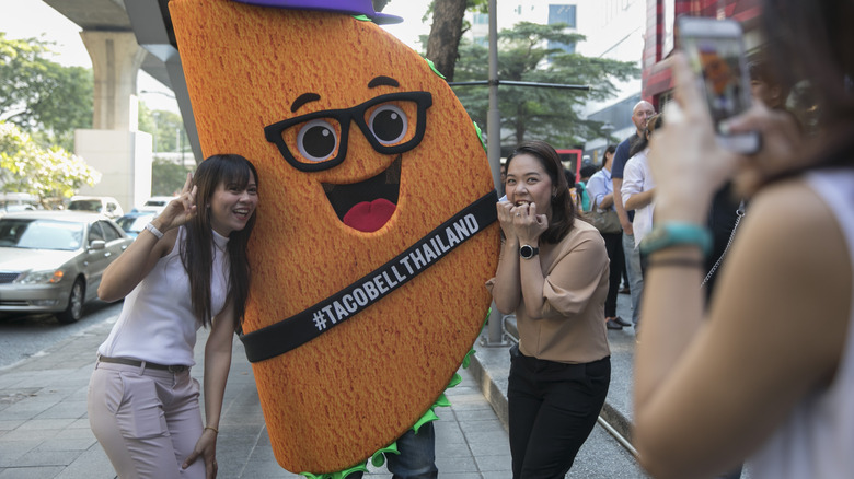 Women pose with taco mascot