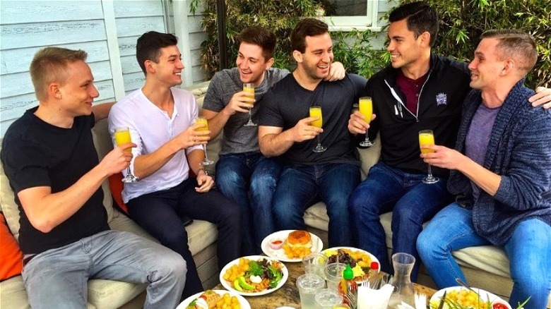 Men sitting together drinking orange juice in champagne flutes