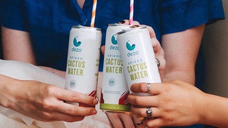 People holding white cans of spiked cactus water