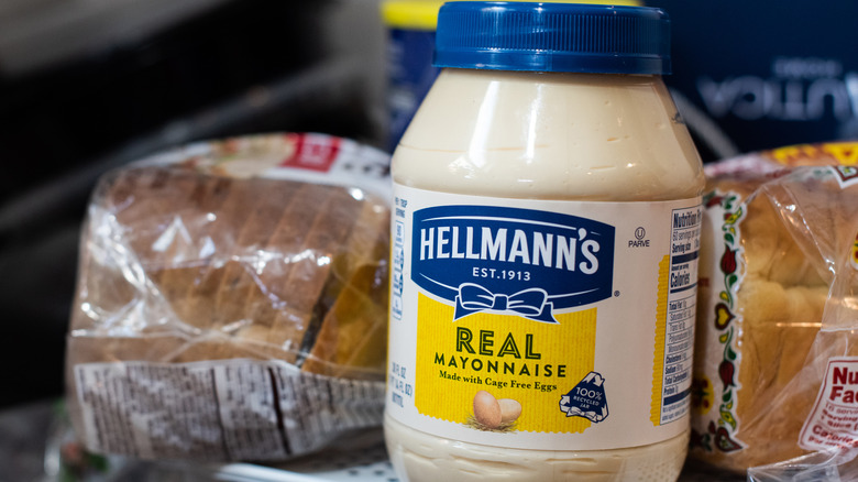 Jar of Hellmann's mayonnaise next to bags of sliced bread.