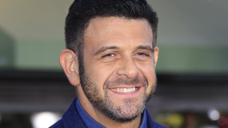 A smiling Adam Richman in blue shirt