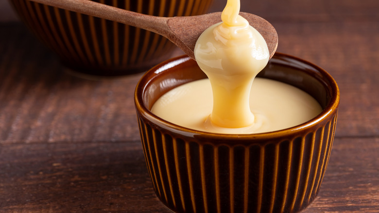 sweetened condensed milk being dripped from spoon to bowl