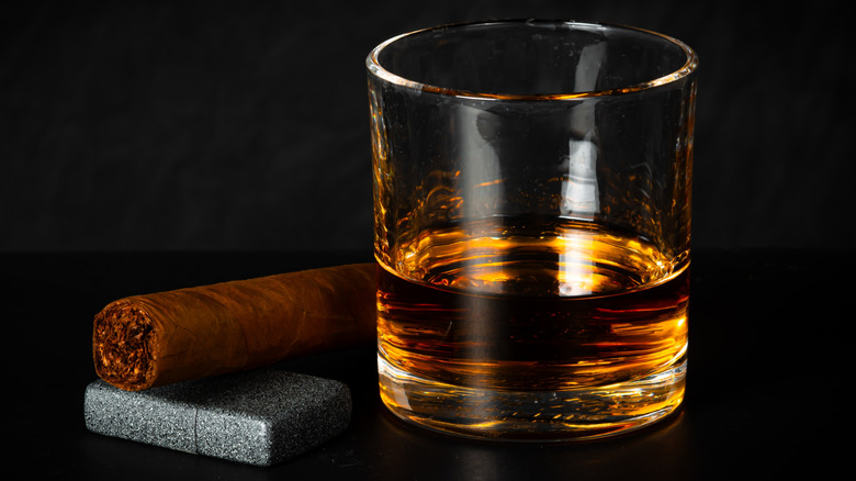 glass of scotch with unlit cigar