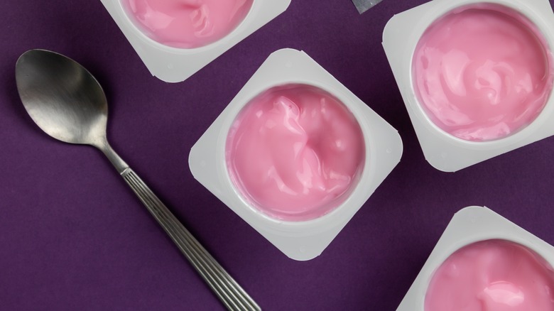 cups of pink, fruit-flavored yogurt and spoon