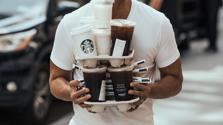 man balancing too many starbucks cups