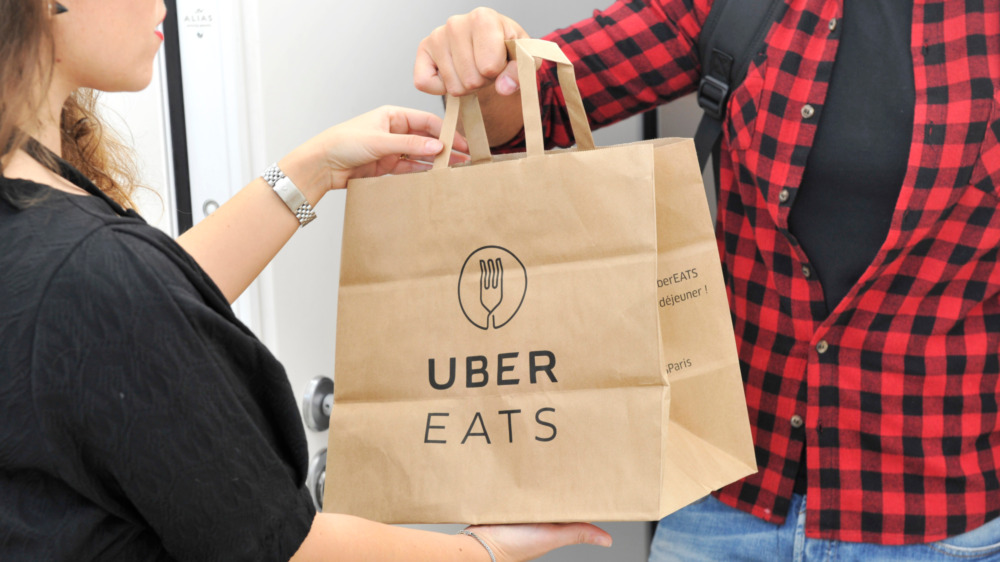Person delivering a brown Uber Eats bag