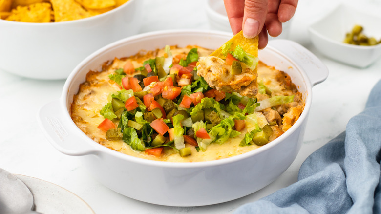 dipping tortilla chip in cheeseburger dip