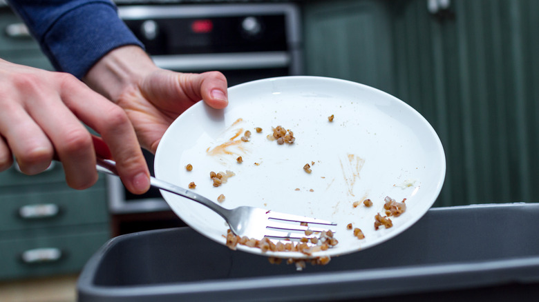 Person scraping plates with fork