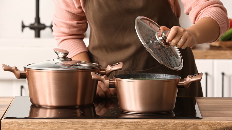 lady removing lid from copper pot