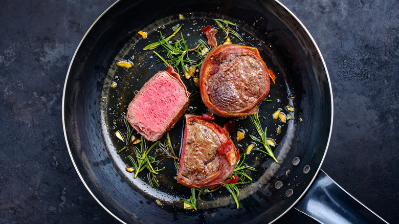 Bacon wrapped filets cooking in pan