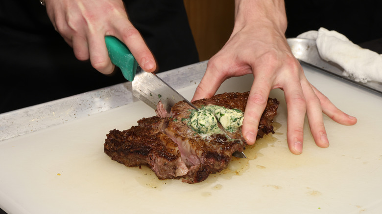 Hands cutting ribeye steak