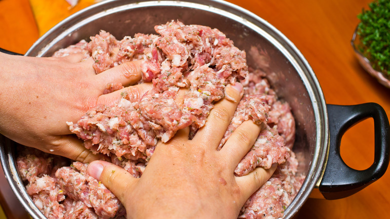 mixing raw sausage with hands