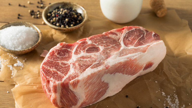 pork butt raw on cutting board with salt and pepper