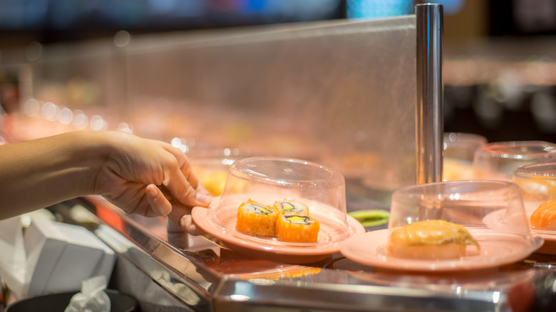 Hand taking sushi plate 