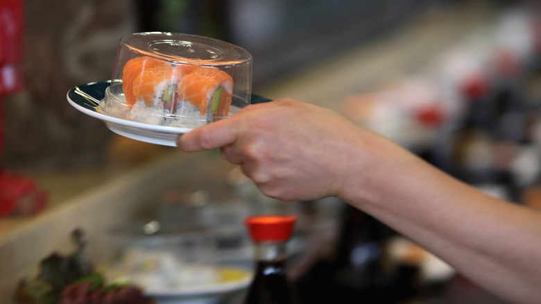 Hand holding sushi roll plate 
