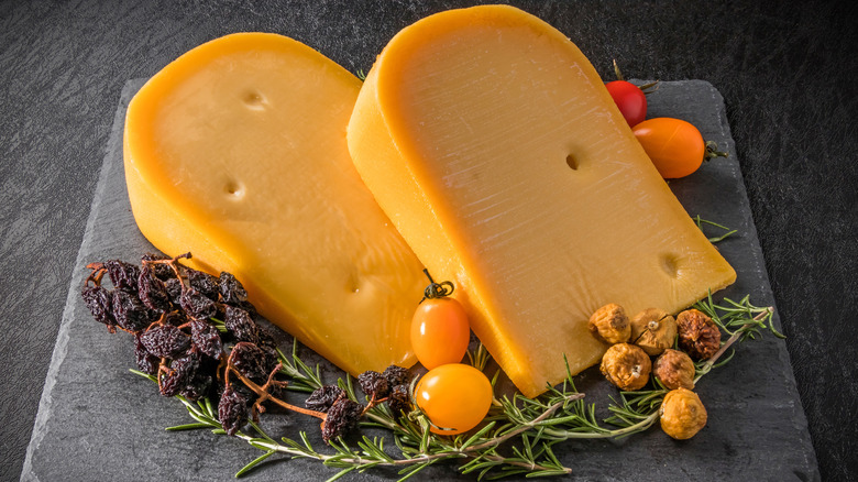 Gouda cheese slices on slate board with granishes