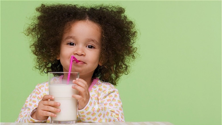 Young girl drinking plant-based milk with straw