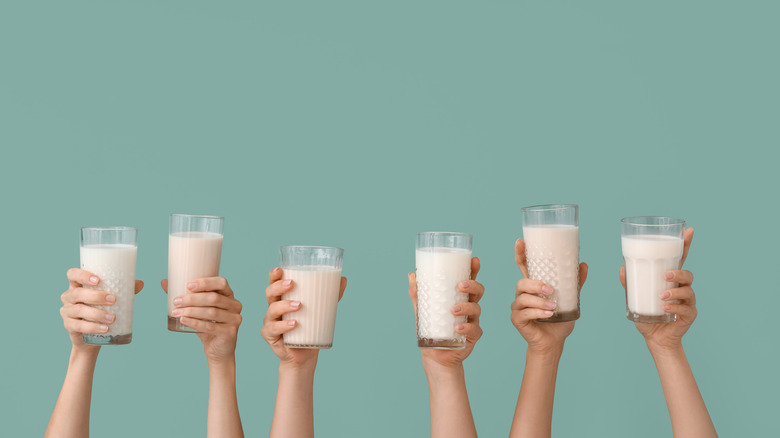 Six hands holding up glasses of milk
