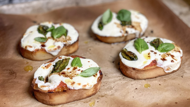 Toasted bread with melted cheese and basil leaves