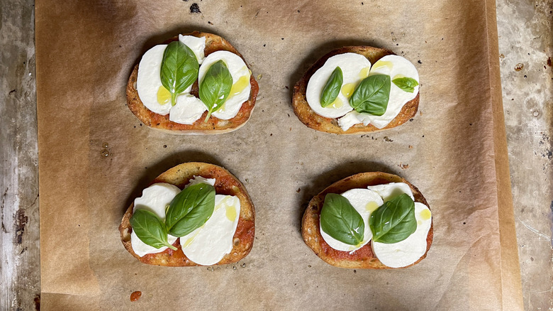 Toasted bread with sliced cheese and basil leaves