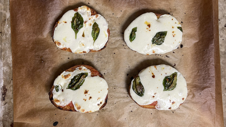 Toasted bread with melted cheese and basil leaves